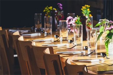 neatly set out table with vases and flowers in clear cups.