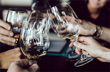 glasses filled with wine clinking together in a group.