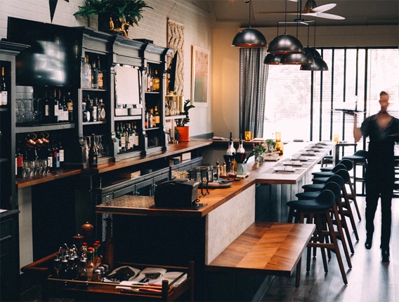 restaurant with wooden bar and accents, black cupboards and dome lights