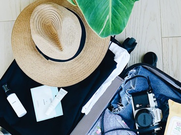 Suitcase with a hat, sunscreen, and a camera